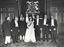 A formal group of Elizabeth in tiara and evening dress with eleven politicians in evening dress or national costume