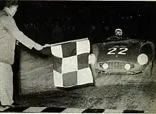 The race director Renzo Castagneto flies the chess flag to the winner Phil Hill on Ferrari.