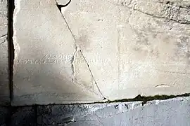 A stone of the gate, repurposed from an older monument: an inscription, now upside-down, is visible