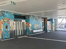 Lift entrance with teal and orange painted artwork along the wall