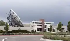 A one-story white building and a large accompanying satellite dish