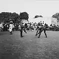 Two youngsters get ready for a wrestling match accompanied by drummers.