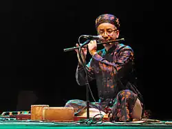 The man is playing the sáo.
