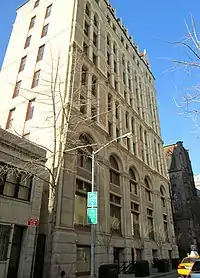A ten-story building with a light-toned brick façade, viewed from street level