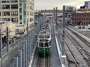 A light rail train on the ramp to a viaduct in an urban area