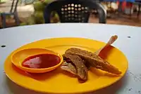 A plate of lekor with a dipping sauce.
