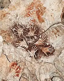 Le «&nbsp;Bouquet de mains&nbsp;», une manifestation remarquable de l’art rupestre de Bornéo, met en scène six mains dans une ronde graphique éternelle. A noter des mains de couleur rouge orangé plus anciennes recouvertes par le motif.