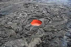 A "skylight" hole, about 6&nbsp;m (20&nbsp;ft) across, in a solidified lava crust reveals molten lava below (flowing towards the top right) in an eruption of Kīlauea in Hawaii