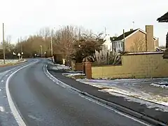 20th century suburban housing in a rural setting. A series of small, modern, houses on the right of a twisty road, with open views to the left.
